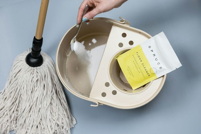Hand adding floor cleaner powder to mop bucket with mop nearby, illustrating shocking things popular kids did in school.