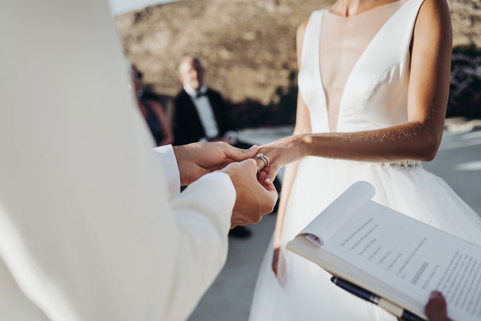 Bride placing ring on groom's finger during outdoor wedding ceremony with Star Wars saga theme inspiration.