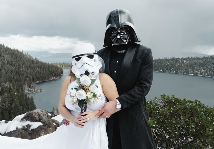 Bride and groom dressed as Star Wars characters pose outdoors at a scenic lake during a themed wedding celebration.