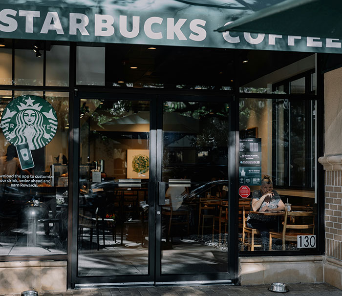 Starbucks storefront with a woman seated inside, related to Florida man arrested after tantrum over Pride flag incident.