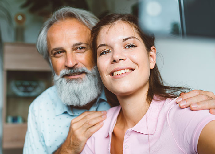 Step-dad and young woman posing closely in home setting illustrating emotional disconnect in blended family relationships.