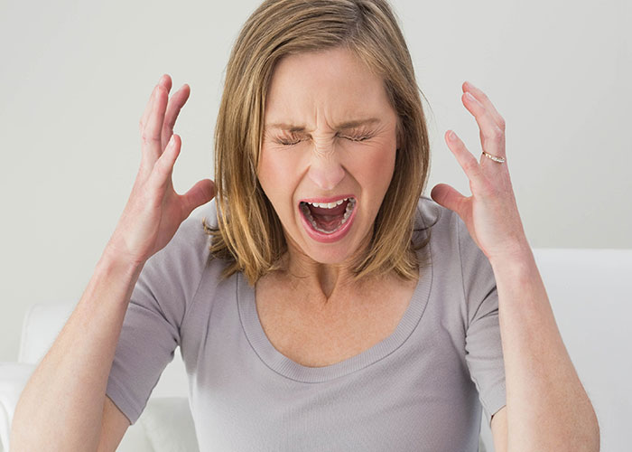Woman in gray shirt showing frustration with hands raised, illustrating emotional tension in step-dad heartbreaking speech scenario.