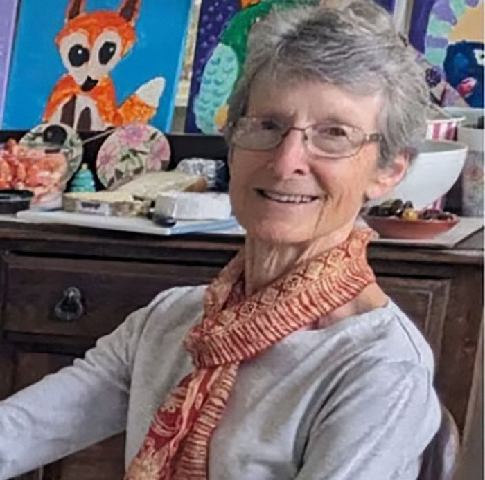 Elderly woman smiling indoors with glasses and scarf, related to daughter revealing final moments stranded on a remote island.