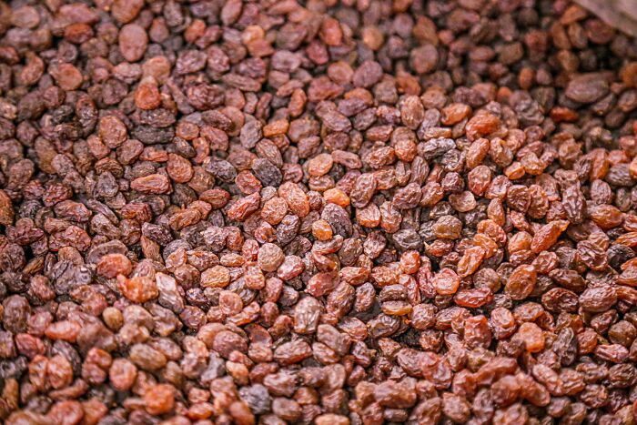 Close-up of a large pile of raisins with varied brown and reddish hues, highlighting texture and natural wrinkles.