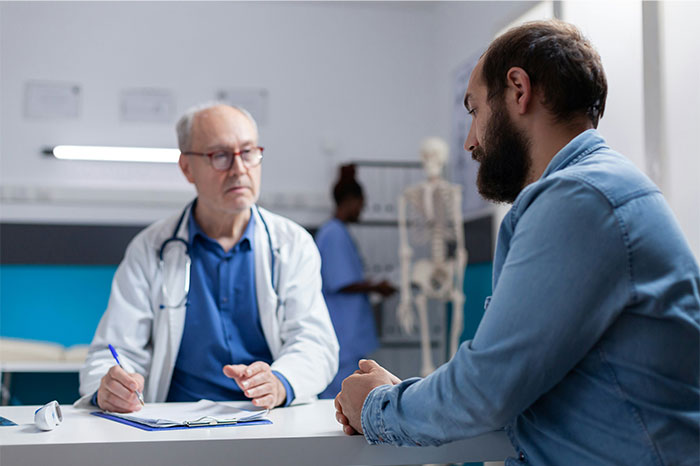 Doctor in a consultation with a patient, discussing symptoms that made people see a doctor related to cancer diagnosis.