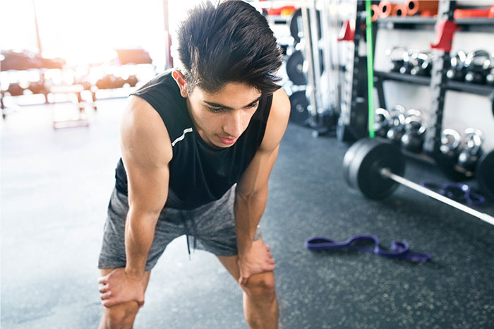 Young man resting in gym after exercise, illustrating symptoms that made people see a doctor and diagnose cancer.