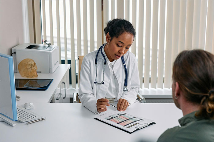 Doctor explaining symptoms to patient during consultation in a medical office, focusing on cancer diagnosis signs.