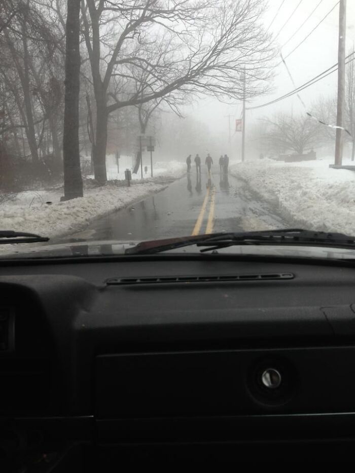 View from inside a car showing a foggy, snowy road with four ghostly figures, a creepy photo that made hearts skip a beat.