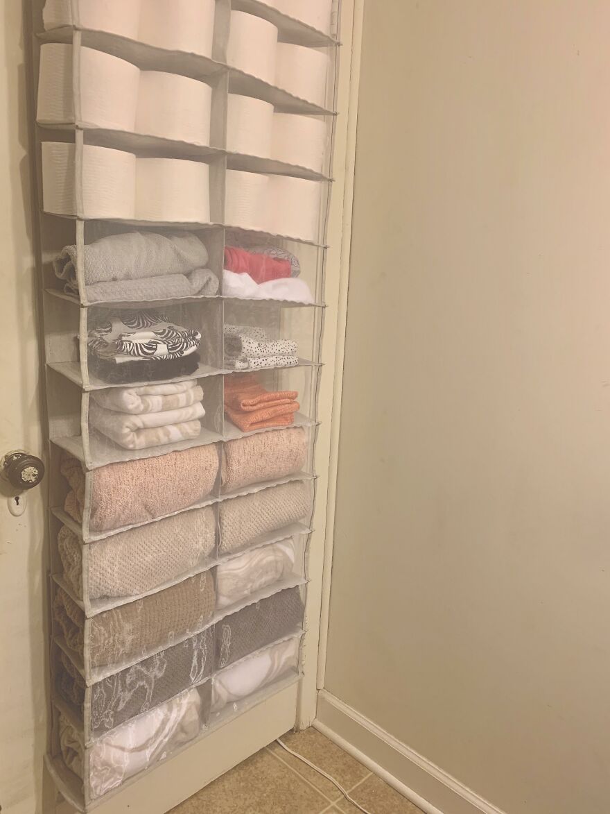 Hanging storage organizer on door efficiently storing towels and folded clothes for home organization hacks.