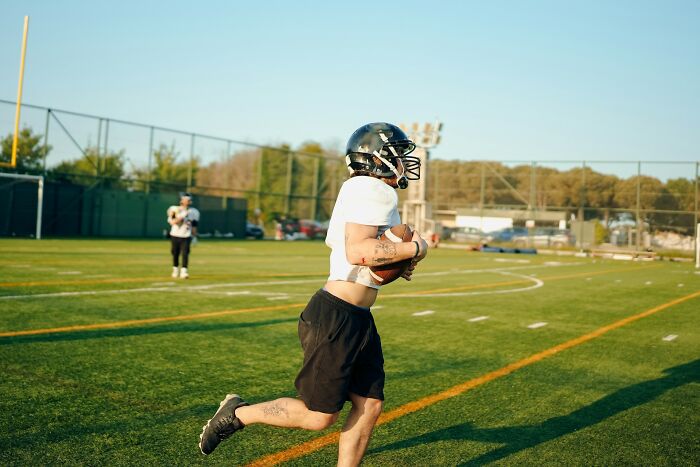 Teen playing football on school field, one of the shocking things popular kids did in school that turned them into outcasts.