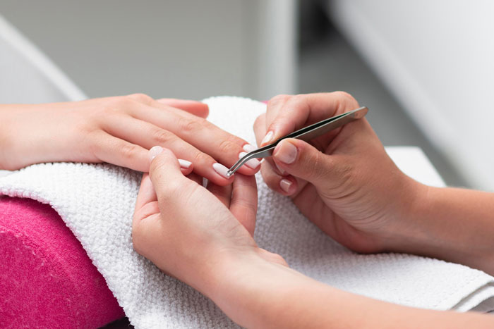 Close-up of a person taking daughters to get nails done with a technician applying nail polish in a salon setting.