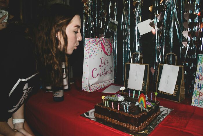 Person blowing out candles on birthday cake at table, illustrating painful table for two moments ending as table for one.
