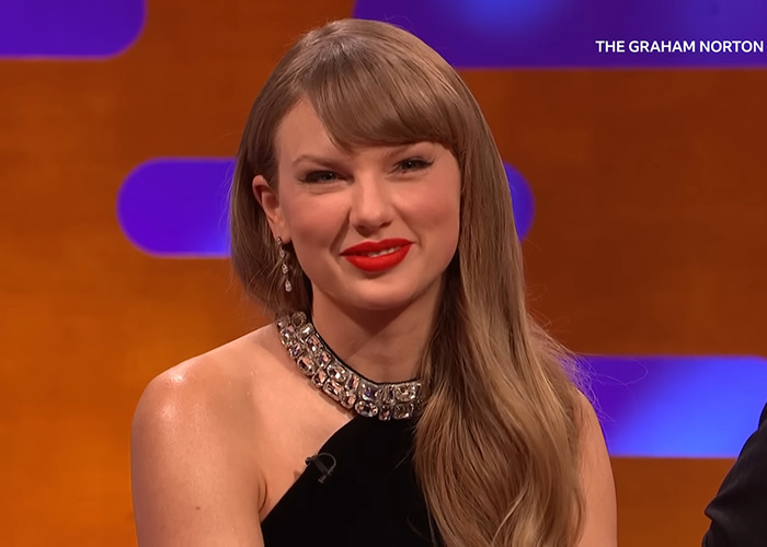 Taylor Swift wearing a black dress with jeweled necklace during a Graham Norton show appearance.