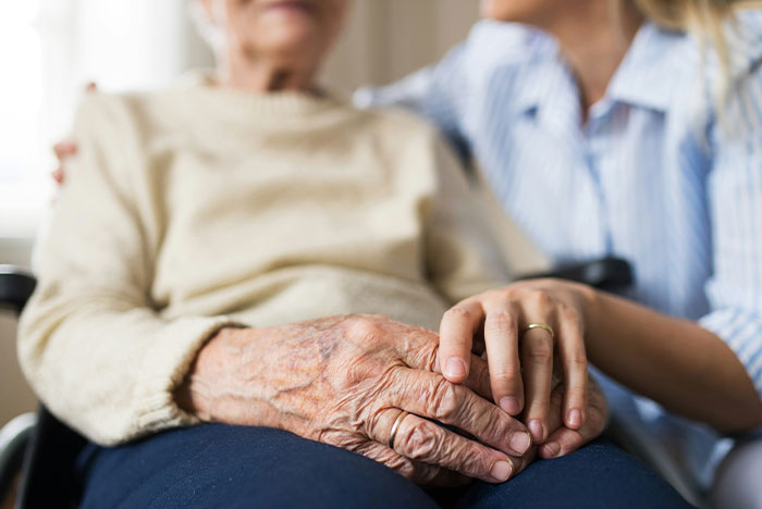 Elderly person holding hands with caregiver, representing parents caring for their disabled son and family challenges. Elderly person holding hands with caregiver, representing parents caring for their disabled son and family challenges.