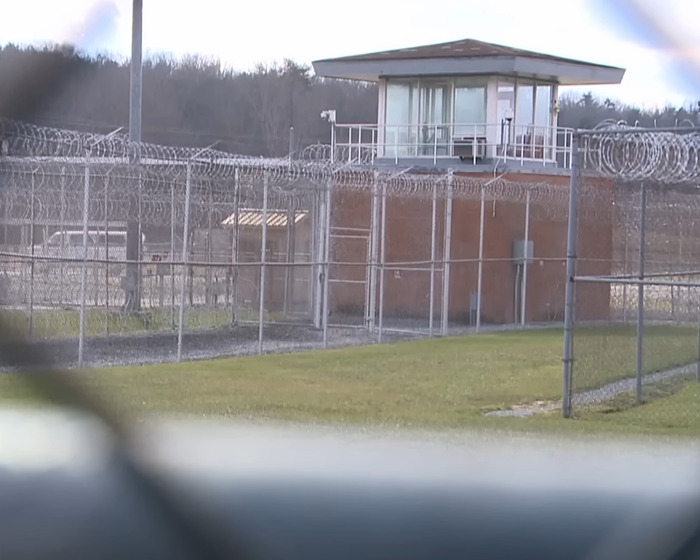 Prison facility with barbed wire fencing and watchtower representing capital punishment for stabbing and pentagram carving case.