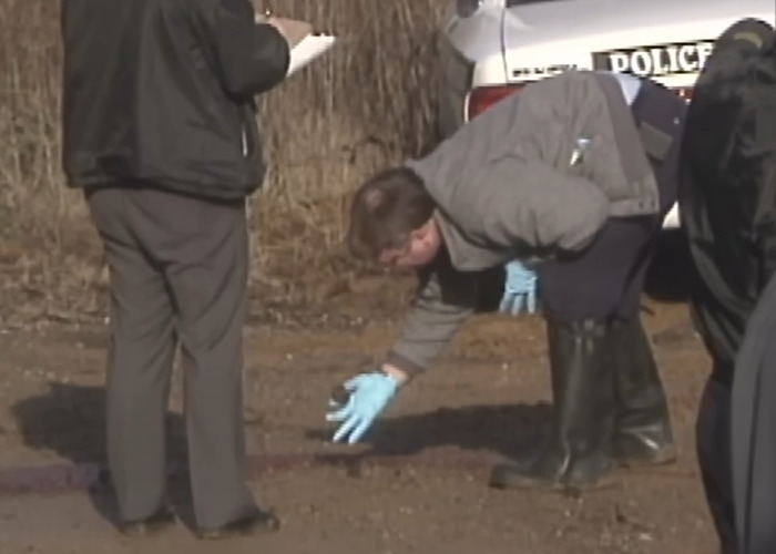 Police investigate crime scene with gloves near vehicle, related to woman&rsquo;s date for capital punishment after stabbing and pentagram carving.