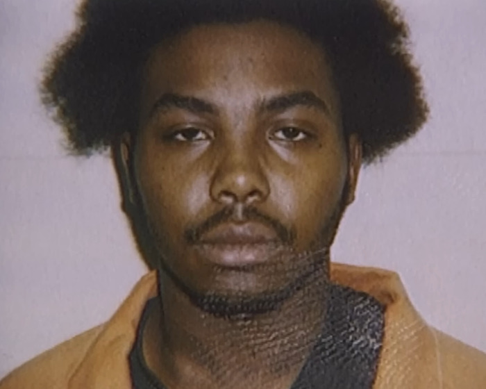 Mugshot of a man with afro hair wearing an orange prison jumpsuit related to stabbing and pentagram crime case.