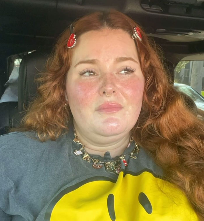 Plus-size model with red hair and a grey shirt sharing her experience of flight attendant fat-shaming mid-flight.