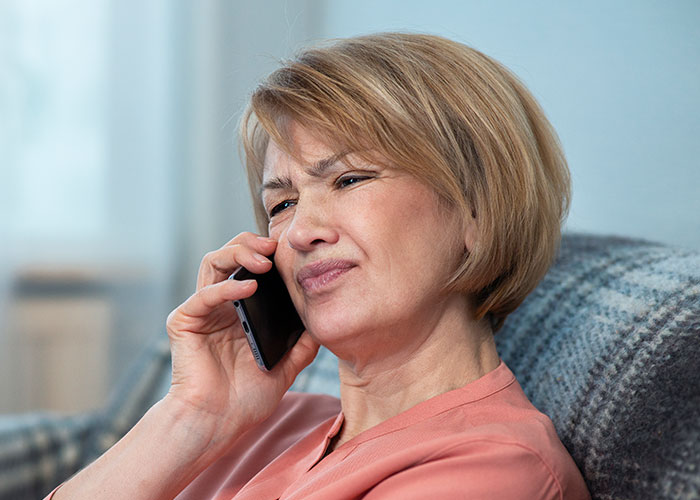 Middle-aged woman looking distressed while talking on the phone, reflecting divorce and Thanksgiving misery themes.