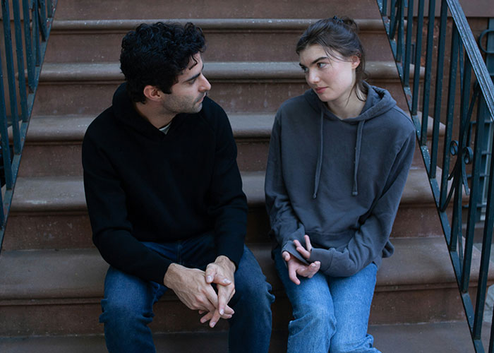 Couple sitting on stairs looking unhappy, illustrating divorce and miserable Thanksgiving emotions.