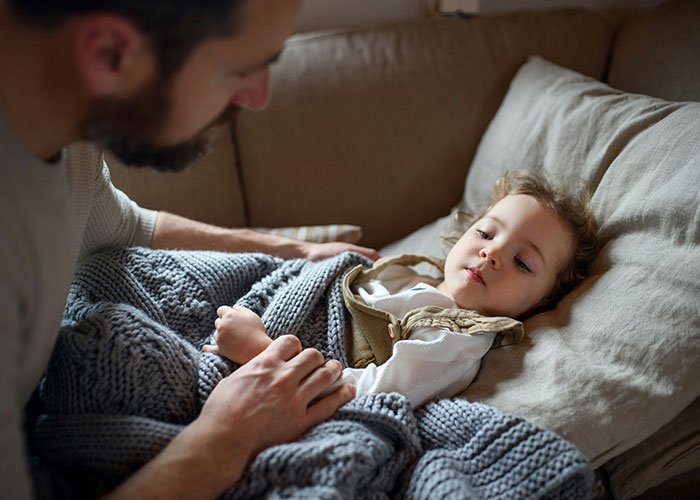 Man comforting sad child lying on couch, capturing the theme of people feeling miserable on Thanksgiving and divorce.