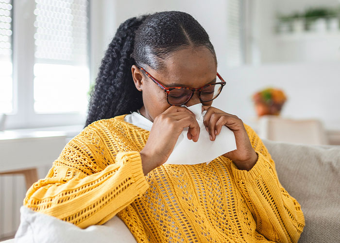 Woman in a yellow sweater wiping tears with a tissue, expressing sadness and misery on Thanksgiving holiday.
