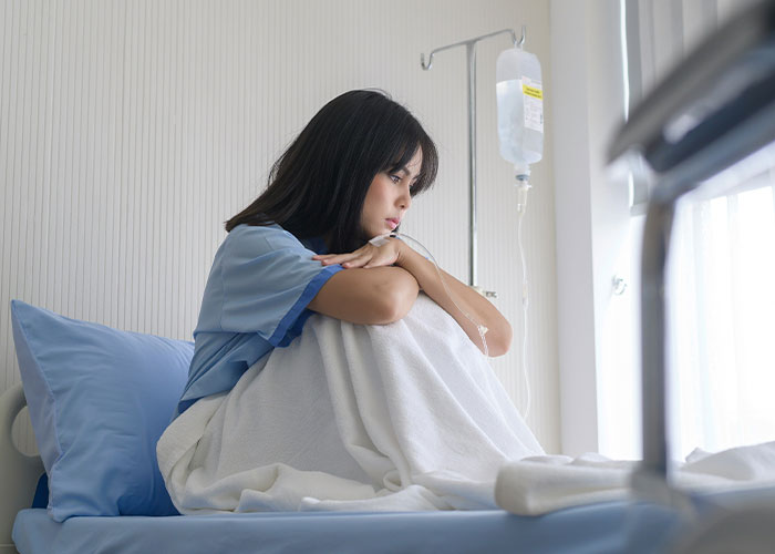 Woman sitting on hospital bed looking sad and lonely representing divorce and misery during Thanksgiving holiday.