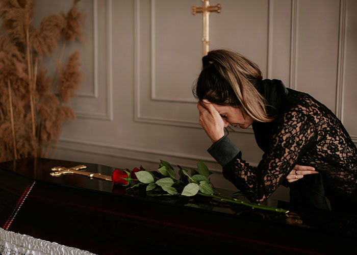 Woman in black lace leaning on a coffin with roses, depicting sadness and misery during Thanksgiving and divorce struggles.