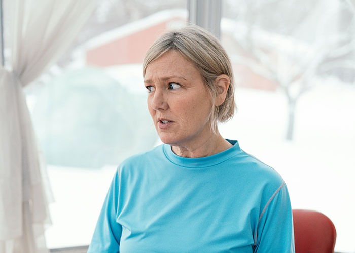 Middle-aged woman in blue shirt looking upset indoors, reflecting the theme of divorce and miserable Thanksgiving moments.