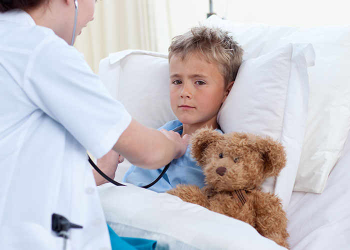 Child looking miserable in hospital bed with teddy bear while nurse checks heartbeat, reflecting Thanksgiving misery and divorce.