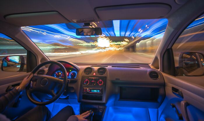 Car interior view at night with blurred city lights outside, illustrating unbelievable facts about countries shared by people.