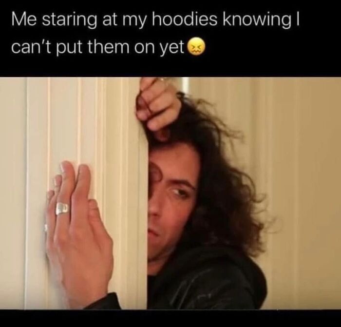 Person peeking from behind a door with a frustrated expression, reflecting relatable memes about hoodies and cozy feelings.