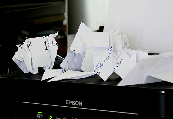 Several paper animals made from printed and handwritten papers placed on top of a black Epson printer, a surprising sight.