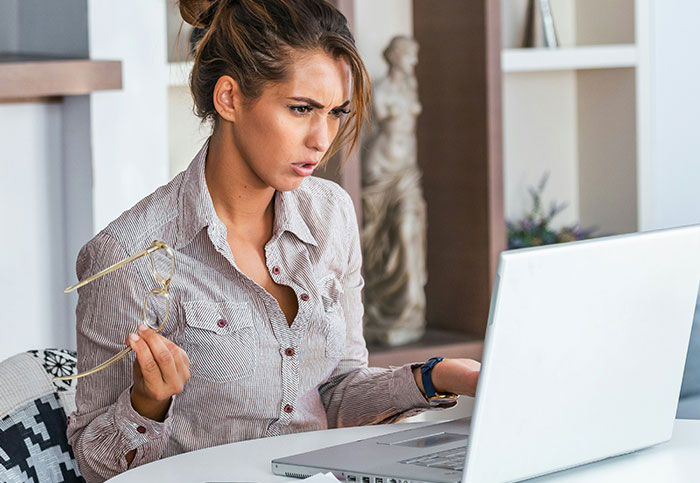 Woman looking surprised at laptop screen, realizing something unexpected, illustrating people realizing what they aren’t supposed to see.
