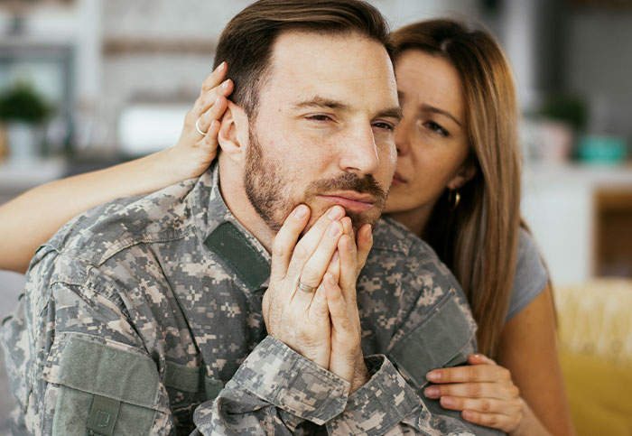 Man in military uniform looking distressed while woman comforts him, capturing moments people realized they aren’t supposed to see