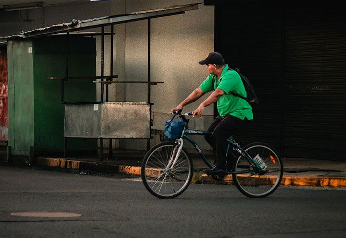 Man in green shirt and black cap riding bicycle on an empty street, a moment people realized they aren’t supposed to see.