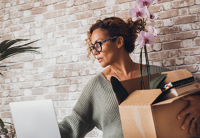 Woman holding a box with plants and notebooks, looking surprised, illustrating times people realized unexpected sights.