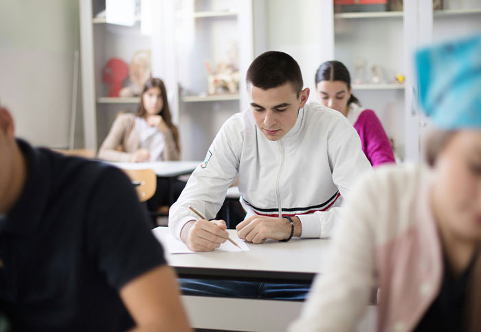 Students taking a test in a classroom, unaware they are seeing something they are not supposed to see.