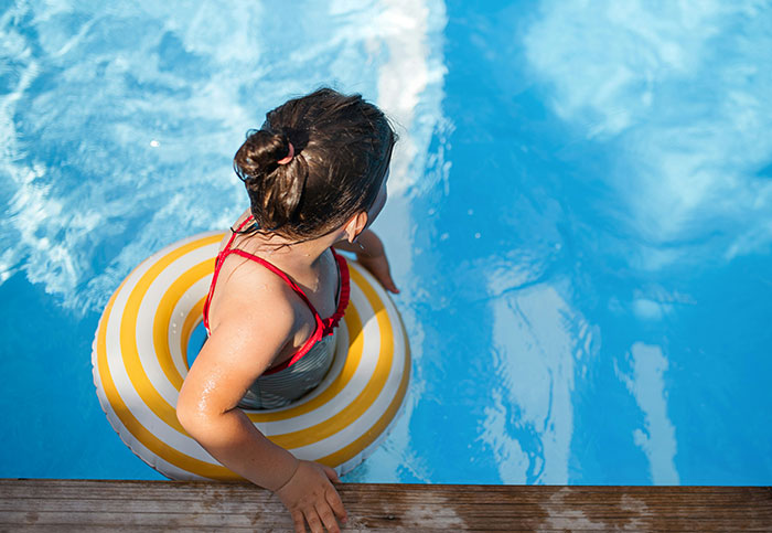 Child in a striped swim ring at the edge of a pool, capturing a moment people realized they aren’t supposed to see.