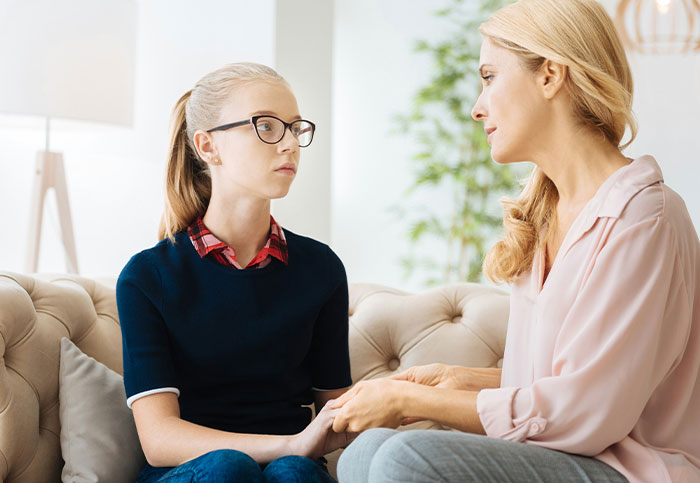 Woman and teenage girl holding hands on a couch, capturing a moment people realized they aren’t supposed to see.