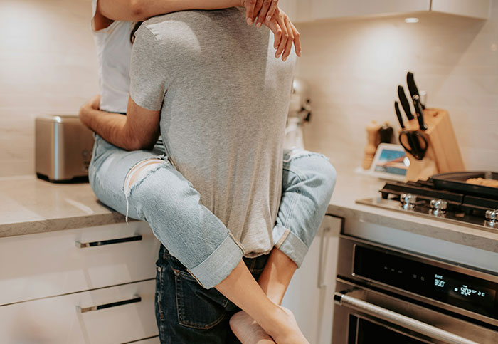 Couple embracing intimately in kitchen, an unexpected moment people realized they aren’t supposed to see.