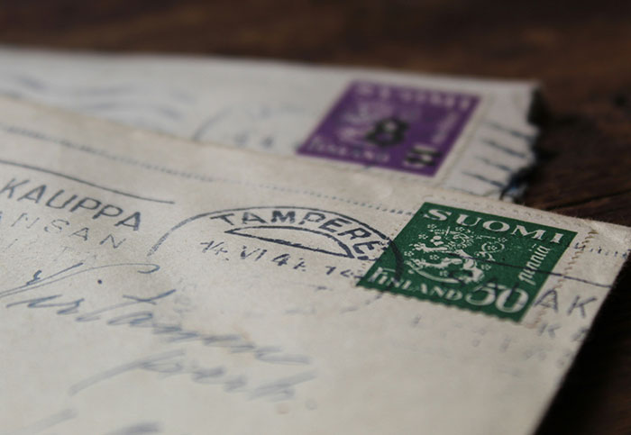 Close-up of vintage Finnish stamps and postmarks on old letters, revealing hidden details people aren’t supposed to see.
