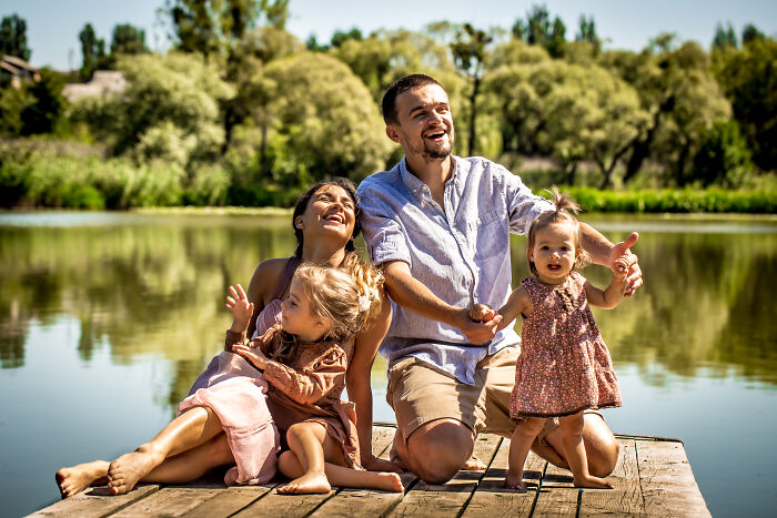 Family enjoying a sunny day by the lake, highlighting the tired mom and let down dad with two young children.