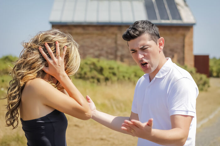 Woman looking tired and frustrated while a man gestures angrily outdoors, depicting a tired mom and let down useless dad.