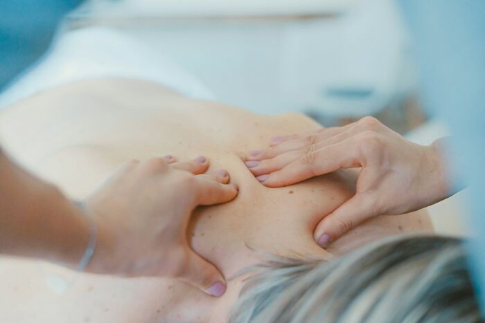 Close-up of hands massaging a person’s back, illustrating strange and dumb health hacks shared by patients.