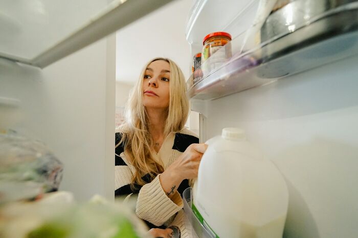 Woman opening refrigerator late at night, illustrating drunk fumbles and bad decisions with food choices.