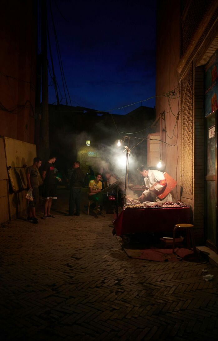 Street food vendor and people at night in a dimly lit alley showcasing unbelievable facts about their countries.