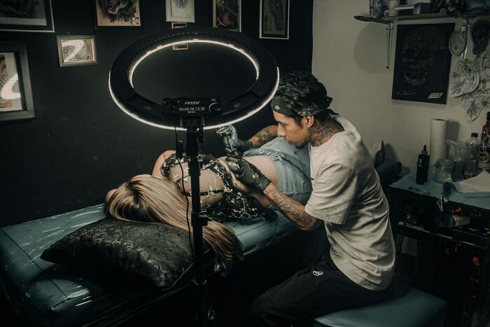 Tattoo artist working on a client in a dimly lit studio, highlighting common tattoo artists messed up moments.