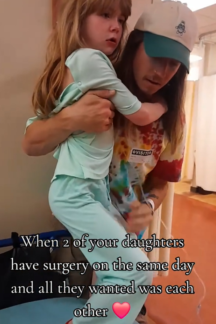 Man comforting young girl in hospital showing heartmelting gesture for two little sisters needing surgery.