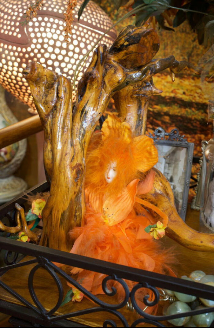 Handcrafted orange doll surrounded by wooden branches and decorative flowers in a surprising Airbnb setting.